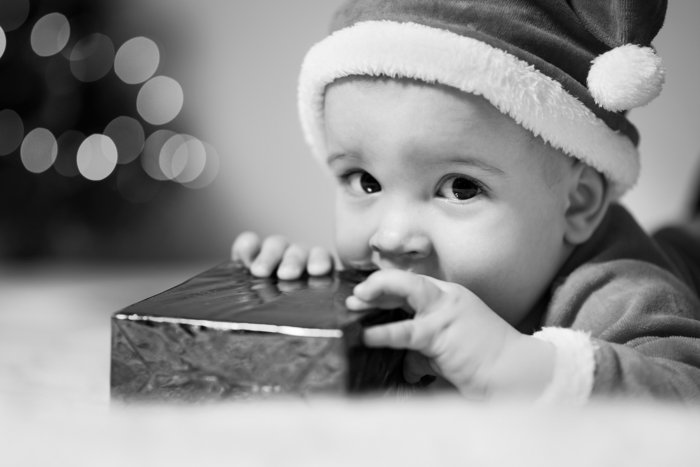 Black and white Christmas portrait of a young boy with a present