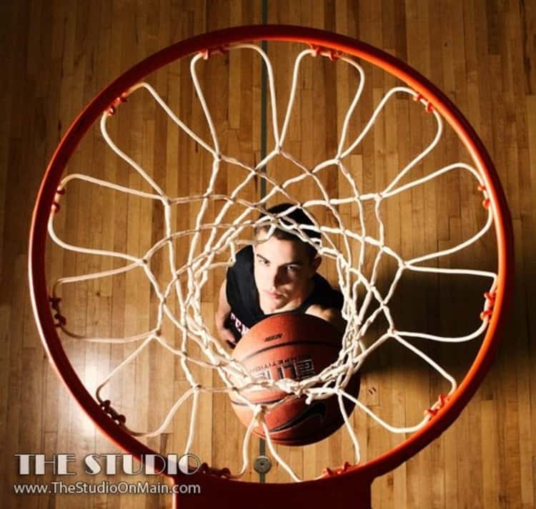 senior picture idea for guys - photo taken from above a basketball hoop of guy looking up and holding basketball