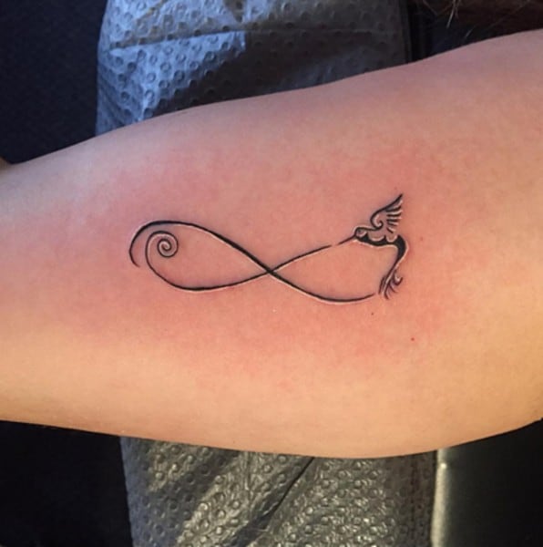 tiny bird in a loop tattoo on arm