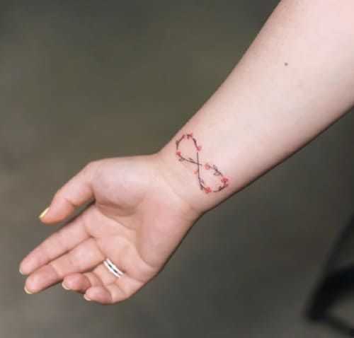 Minimal botanical tattoo with red details on wrist