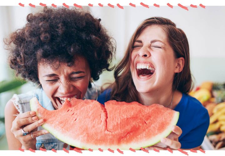 two women laughing and eating watermelon
