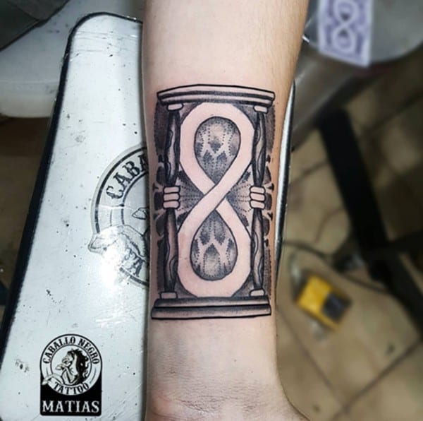 Infinity symbol inside hourglass tattoo on arm
