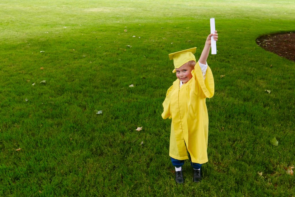 Boy graduating from preschool holds up his diploma