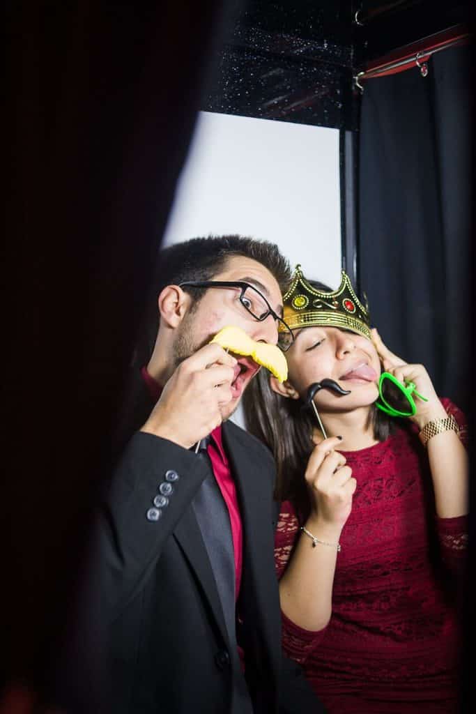 Couple posing in photo booth with fake mustaches