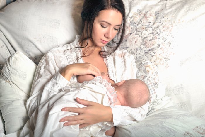 Newborn photo idea of the mother feeding the baby in bed