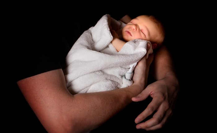 Sweet newborn photo idea of the baby cradled in the fathers arms