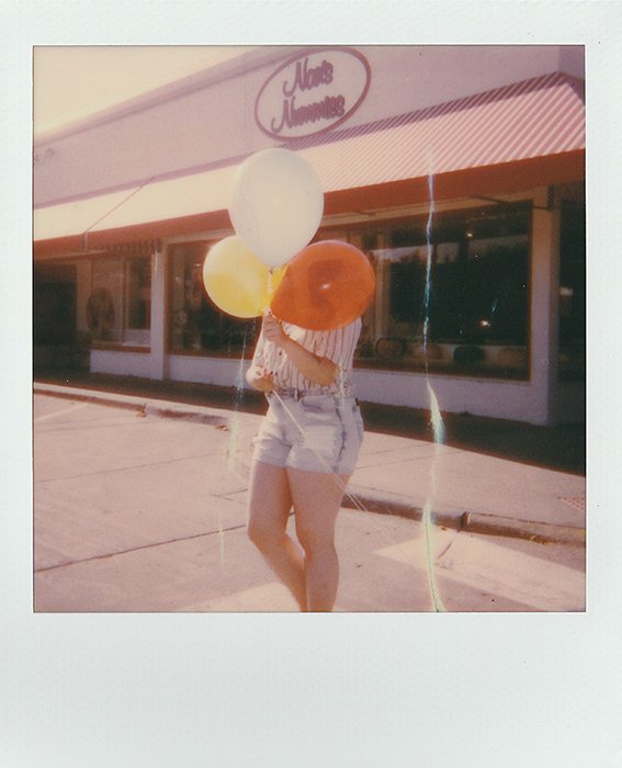 Polaroid picture of a woman with balloons in her hands