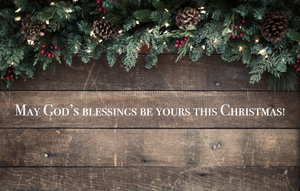 Christmas garland on an old wood background with a religious Christmas blessing.