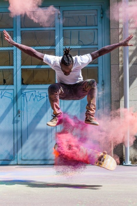 photo of a skateboarding doing a trick with color powder